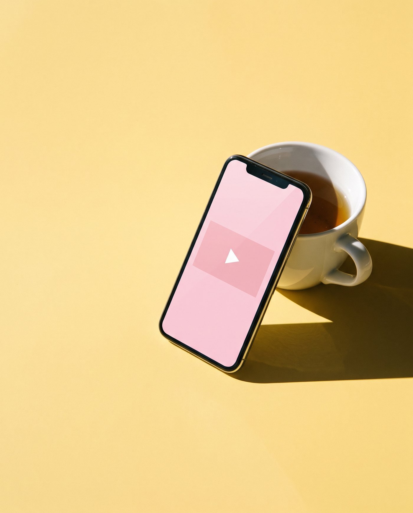 A phone propped against a cup of tea, playing a lesson