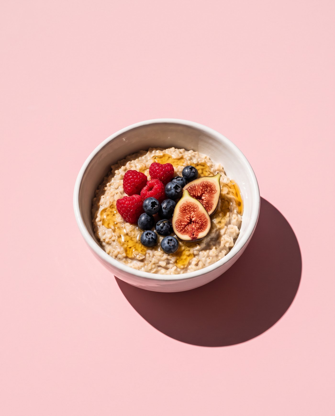 A bowl of warm porridge with berries, figs and honey
